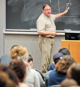 Economics professor Michael Coiner points to a classroom blackboard